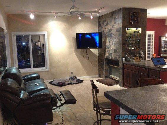 Living room with leather sofa, fireplace, TV, and a bar area with a laptop