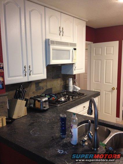 Kitchen counter with a toaster, gas stovetop, microwave, sink, and cabinets
