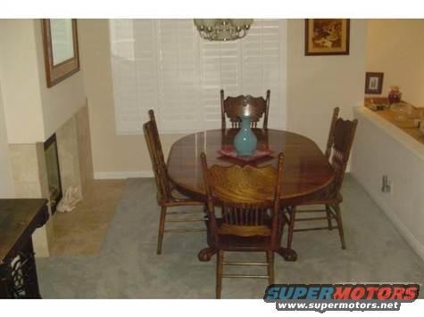 Dining room with oval wooden table, four chairs, fireplace, and window blinds