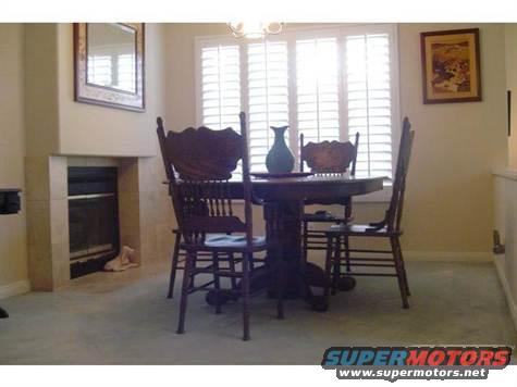 Dining room with a wooden table, four chairs, a fireplace, and a mirror on the wall