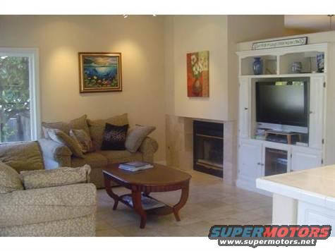 Living room scene with fireplace, couch, coffee table, and entertainment center