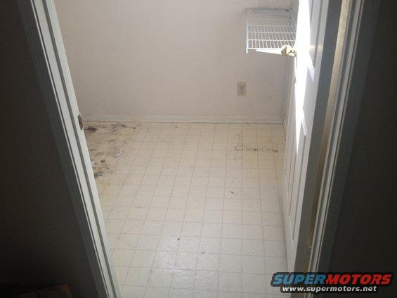 Interior room with white tiled floor and a wire shelf on the wall