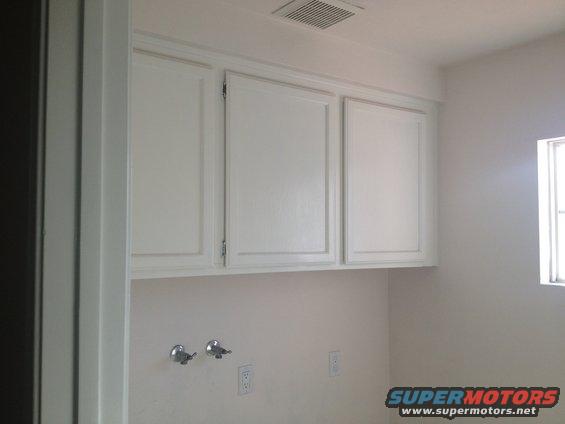 Interior room scene with white cabinets, plumbing fixtures, and a window