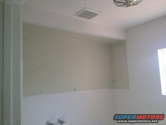 interior wall with a shelf above it, vent in ceiling, and a window on the right