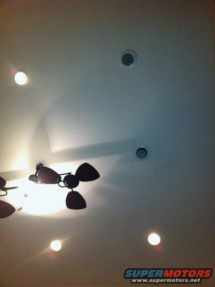 Ceiling with two dark ceiling fans and several recessed lights. A watermark reads SUPERMOTORS