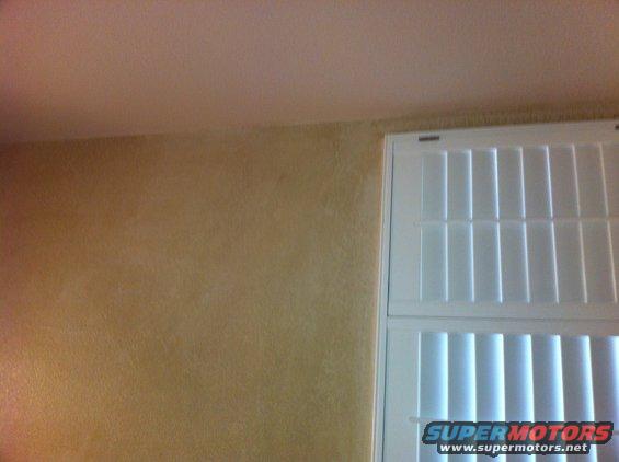 Interior wall with textured finish next to white louvered shutters. "SUPER MOTORS" logo visible