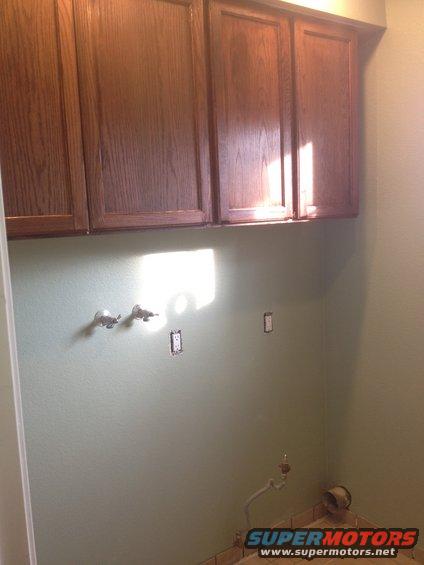 Interior room scene with wooden cabinets and exposed plumbing