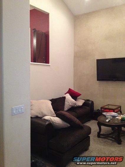 Living room with a dark brown sectional couch, pillows, coffee table, and a wall-mounted TV