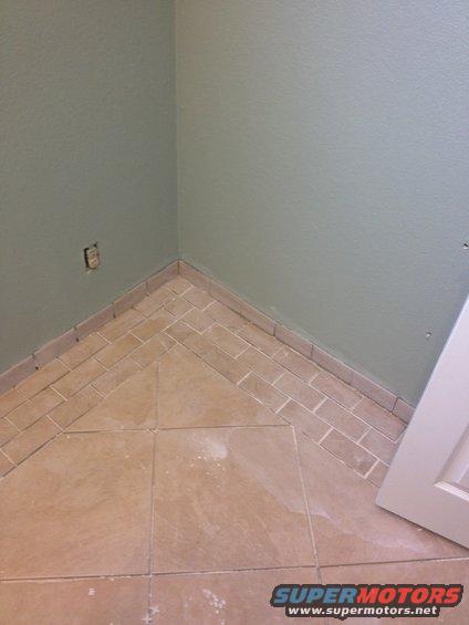 Interior corner with tiled floor and light green walls, Supermotors.net logo visible