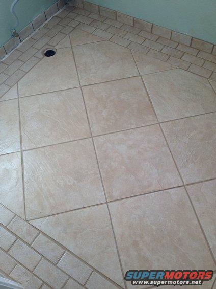 tiled floor with a drain in the corner, bordered by smaller tiles