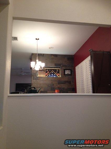 Interior view of a room with a chandelier, stone accent wall, and a display case with a flag