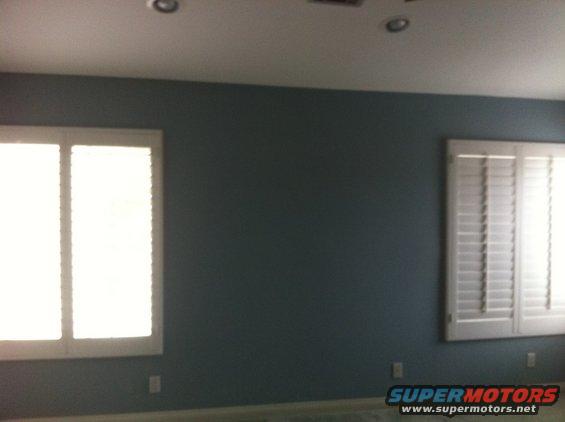 Interior room with dark blue walls, two windows with white shutters, and a watermark for Supermotors.net