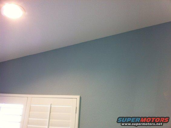 Interior shot showing a ceiling light, a light blue wall, and white shutters