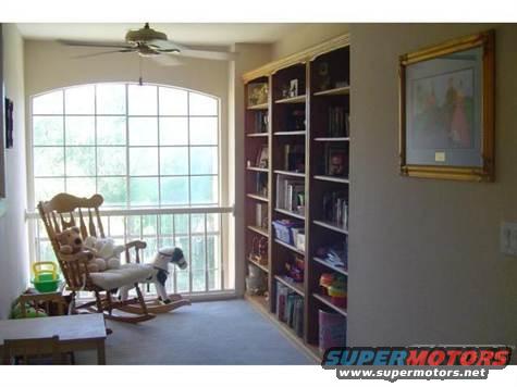 Interior scene with rocking chair, bookshelves, and a large window
