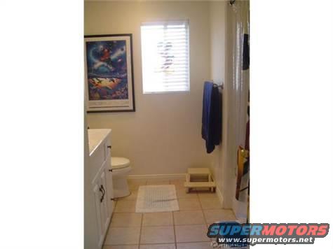 bathroom with toilet, sink, shower, and a framed picture on the wall