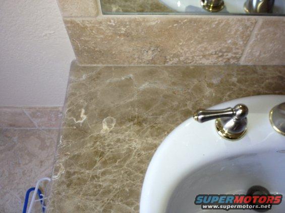 Bathroom sink with marble countertop and faucet. Supermotors.net logo visible