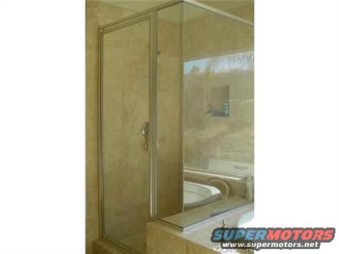 Glass shower stall with tiled walls and a bathtub visible inside