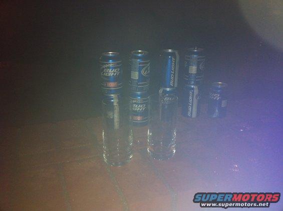 Bud Light cans stacked on drinking glasses on a wooden surface