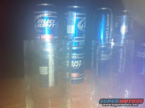 Several Bud Light cans stacked on top of glasses
