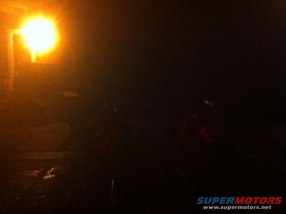 Two red sports cars parked at night under a bright light