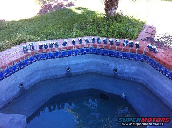 Hot tub with numerous beer cans lined up on the brick rim