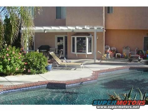 Backyard scene with a swimming pool, patio furniture, and a house