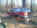 1978 Ford Bronco - Jeep Cherokee XJ being worked on, raised on barrels in a forest setting.