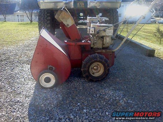 red snow blower in front of a truck with a license plate that reads 8759 WISCONSIN