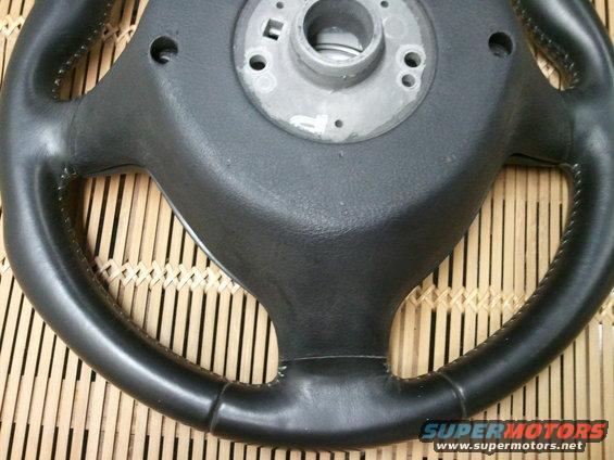 Close-up of a black leather steering wheel with a metal hub