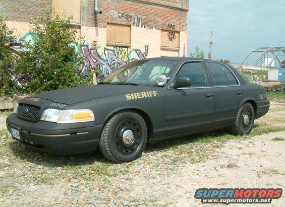 2003 Ford Crown Victoria police car with "SHERIFF" text on door, matte black paint, and steel wheels