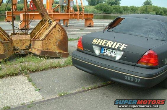 2003 Ford Crown Victoria Sheriff car parked next to a large industrial claw