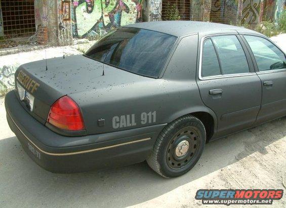 2003 Ford Crown Victoria police car with 'SHERIFF' on trunk and 'CALL 911' on fender