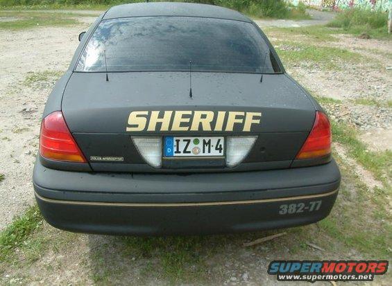 Rear view of black Ford Crown Victoria with 'SHERIFF' in gold letters. License plate is IZ-M-4