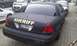 2003 Ford Crown Victoria - A black Ford Crown Victoria, marked as a Sheriff vehicle, is parked in a lot with other cars and vans.