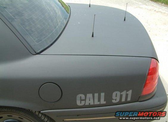 Matte black 2003 Ford Crown Victoria rear with "CALL 911" text and antennas