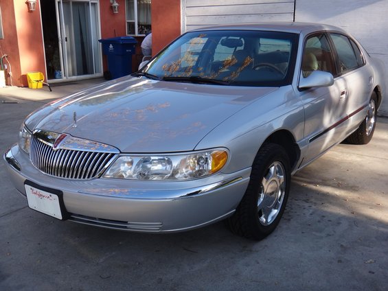 Silver 2000 Lincoln Continental sedan parked on concrete, front 3/4 view, showing chrome grille and headlights