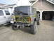 1974 Ford Bronco - A modified Ford Bronco is parked in front of a garage, with a silver pickup truck beside it.