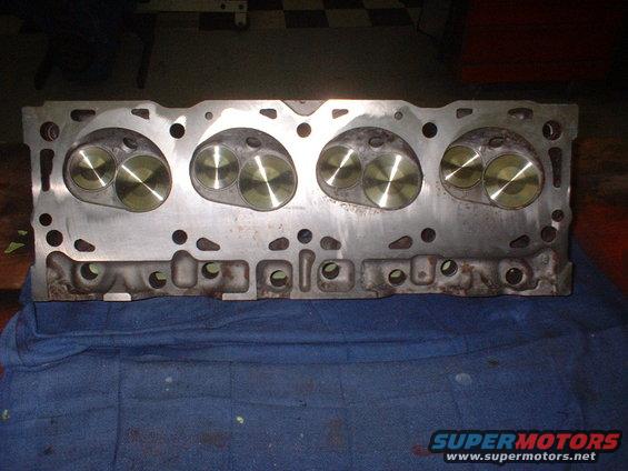 Engine cylinder head with four sets of valves visible, resting on a blue cloth