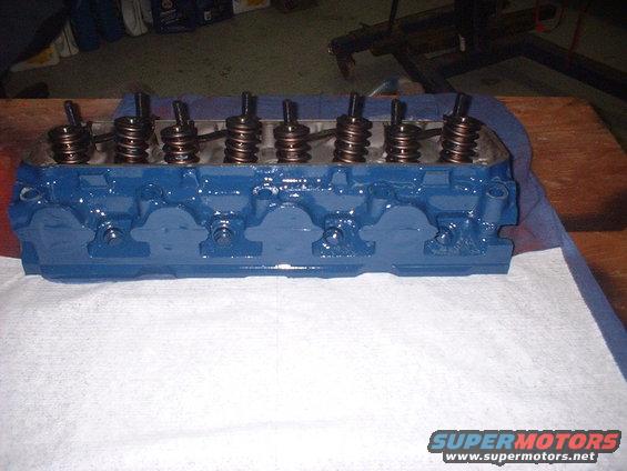Blue painted engine cylinder head with visible valve springs and pushrods