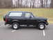 1996 Ford Bronco - A black 1996 Ford Bronco SUV is parked on an asphalt lot, viewed from the side with a spare tire mounted on the rear.