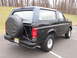 1996 Ford Bronco - Rear view of a black 1996 Ford Bronco, showing the spare tire and license plate.