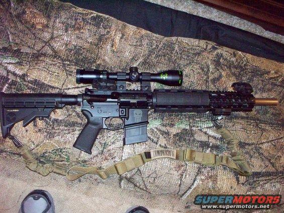 Assault rifle with scope and sling on camouflage background