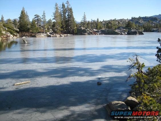 frozen lake with trees and rocks on a clear day