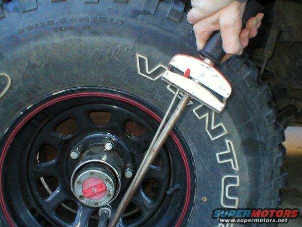 Torque wrench being used on the lug nuts of a large off-road tire