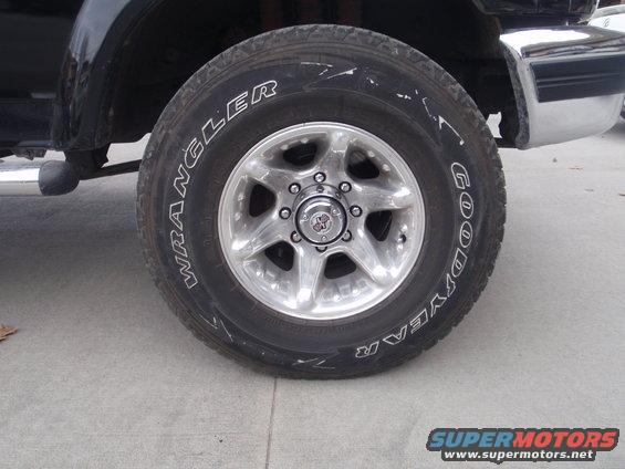 Close-up of a Goodyear Wrangler tire on a vehicle's front wheel. Chrome bumper visible