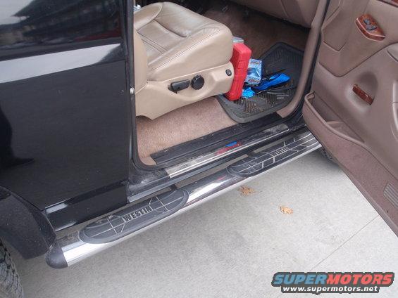 driver's side door open showing tan leather seat, Westin running boards, and floor mat with items on it
