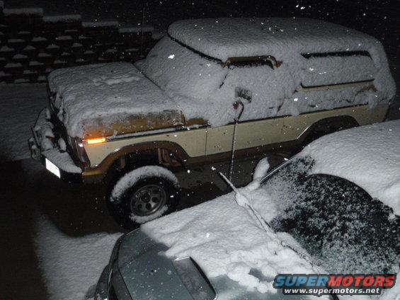 1978 Ford Bronco, beige and brown, covered in snow, parked next to another snow-covered car