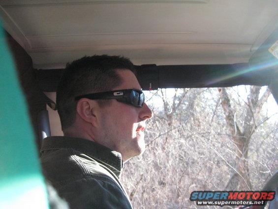 Man in sunglasses driving a 2005 Jeep Wrangler, side profile, interior view