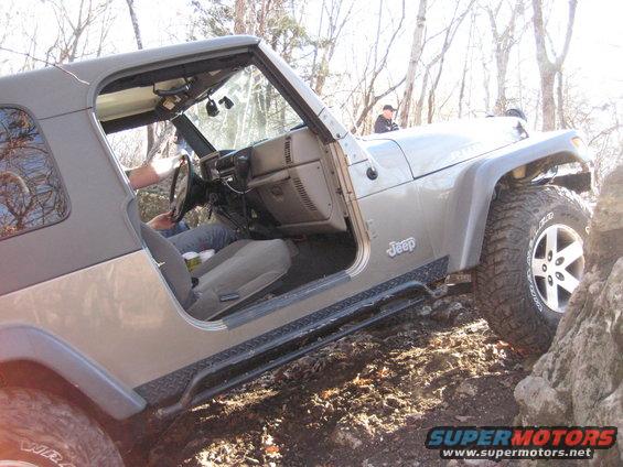 Silver Jeep Wrangler with soft top off-road on rocky terrain