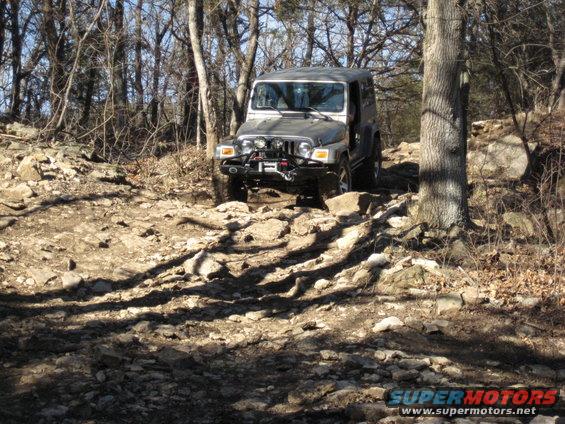 Silver 2005 Jeep Wrangler driving on a rocky trail